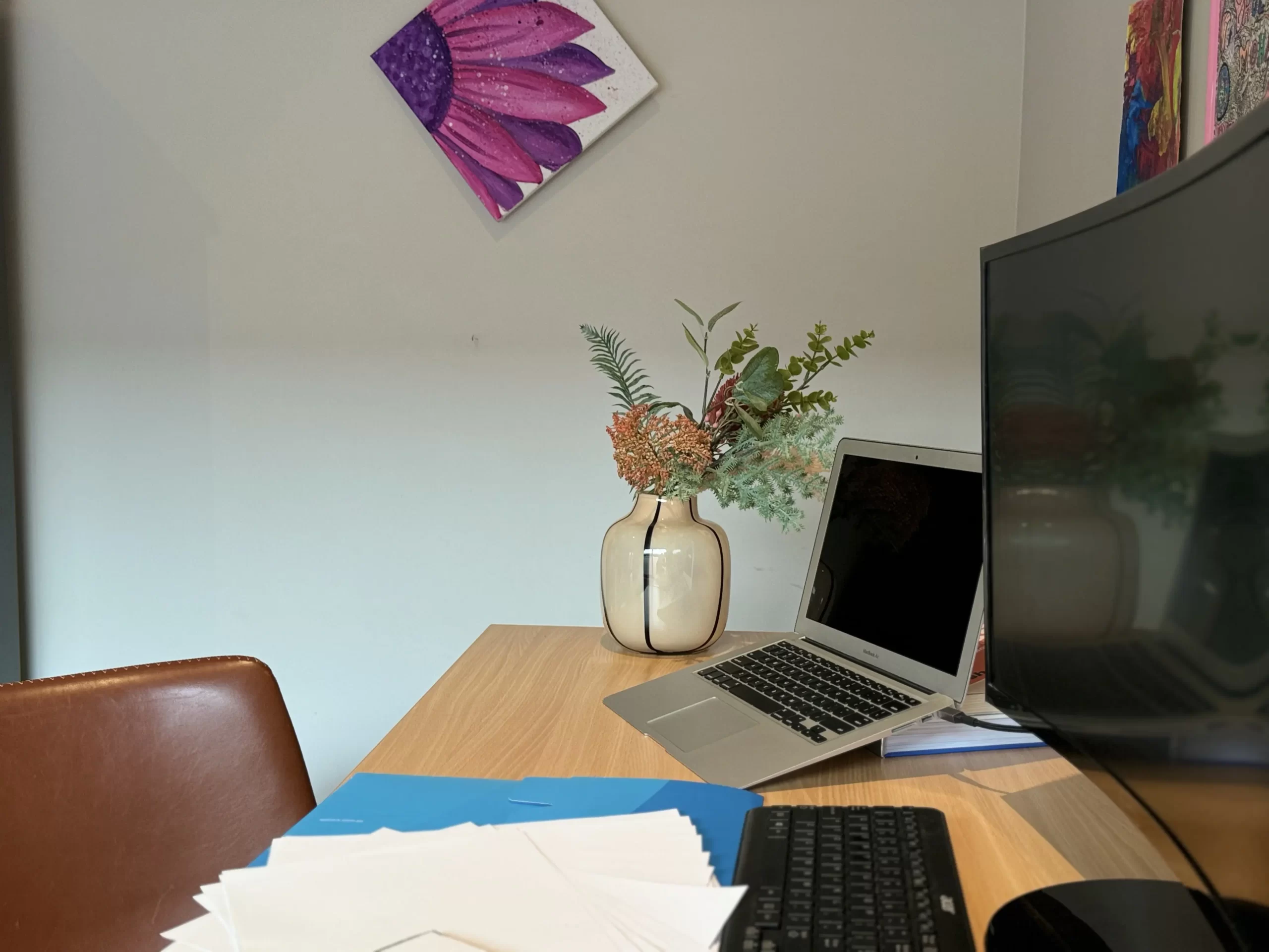 Graphic design studio workspace with a computer, plant, and colorful artwork on the wall- Homepage